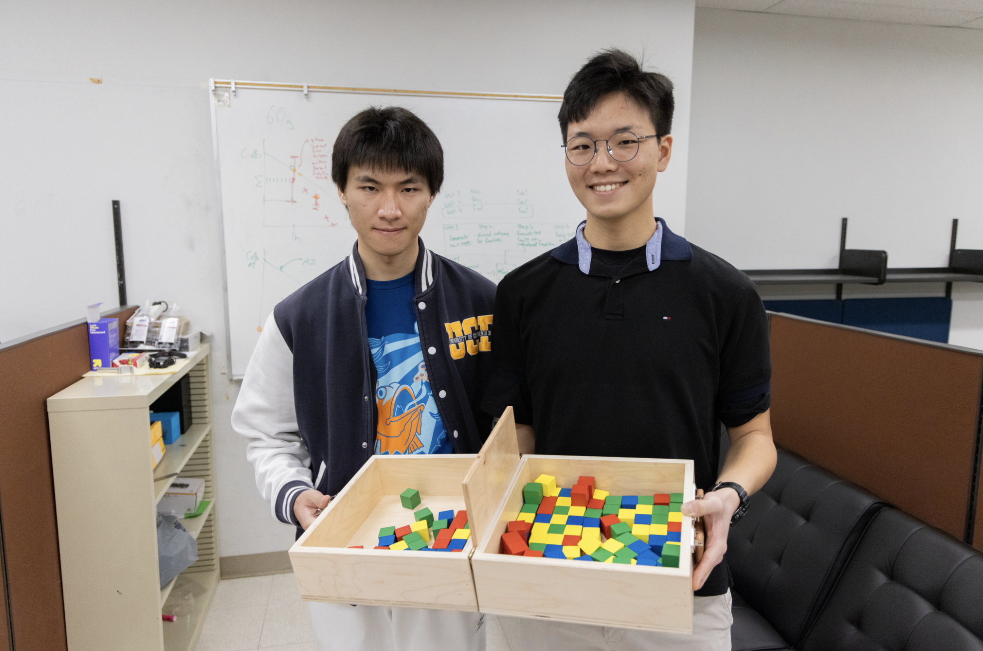 Computer science graduate students Ziqiang "Joe" Zhu, left, and Jun Min Kim pose with the Box and Blocks Test. (Elena Troncoso/UC Davis