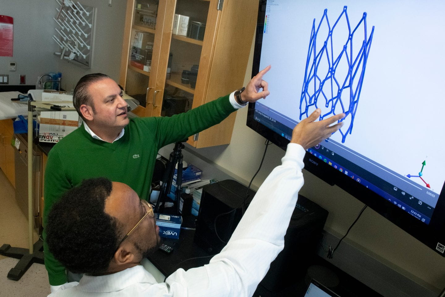 Nnaoma Agwu (pointing), a Ph.D. candidate in biomedical engineering at UC Irvine, and his advisor, professor Arash Kheradvar, examine an image illustrating the transcatheter implantation of the Iris Valve. Steve Zylius / UC Irvine Nnaoma Agwu (pointing), a Ph.D. candidate in biomedical engineering at UC Irvine, and his advisor, professor Arash Kheradvar, examine an image illustrating the transcatheter implantation of the Iris Valve. Steve Zylius / UC Irvine