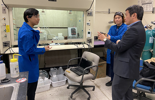 Thirawit Sornsuchat (left) and Hung-Ming Chang (right) speak with U.S. Rep Dave Min in the electrochemistry lab. 