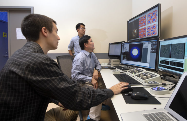 Christopher Addiego (left), a UCI graduate student in physics & astronomy; Xiaoqing Pan (seated in center), UCI’s Henry Samueli Endowed Chair in Engineering and a professor of both materials science & engineering and physics & astronomy; and Wenpei Gao (standing), a UCI postdoctoral researcher in materials science & engineering, were able to visualize the electric charge density of materials at sub-angstrom resolution using a new scanning transmission electron microscopy technique. Steve Zylius / UCI